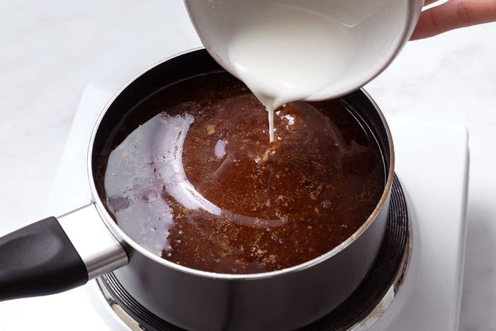 Cornstarch and water mixture being poured into the cooking juices in a saucepan for step four of Teriyaki Chicken Thighs recipe for Taste of Home