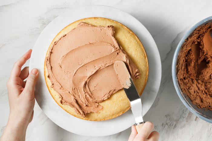 A person is frosting the top of a cake.