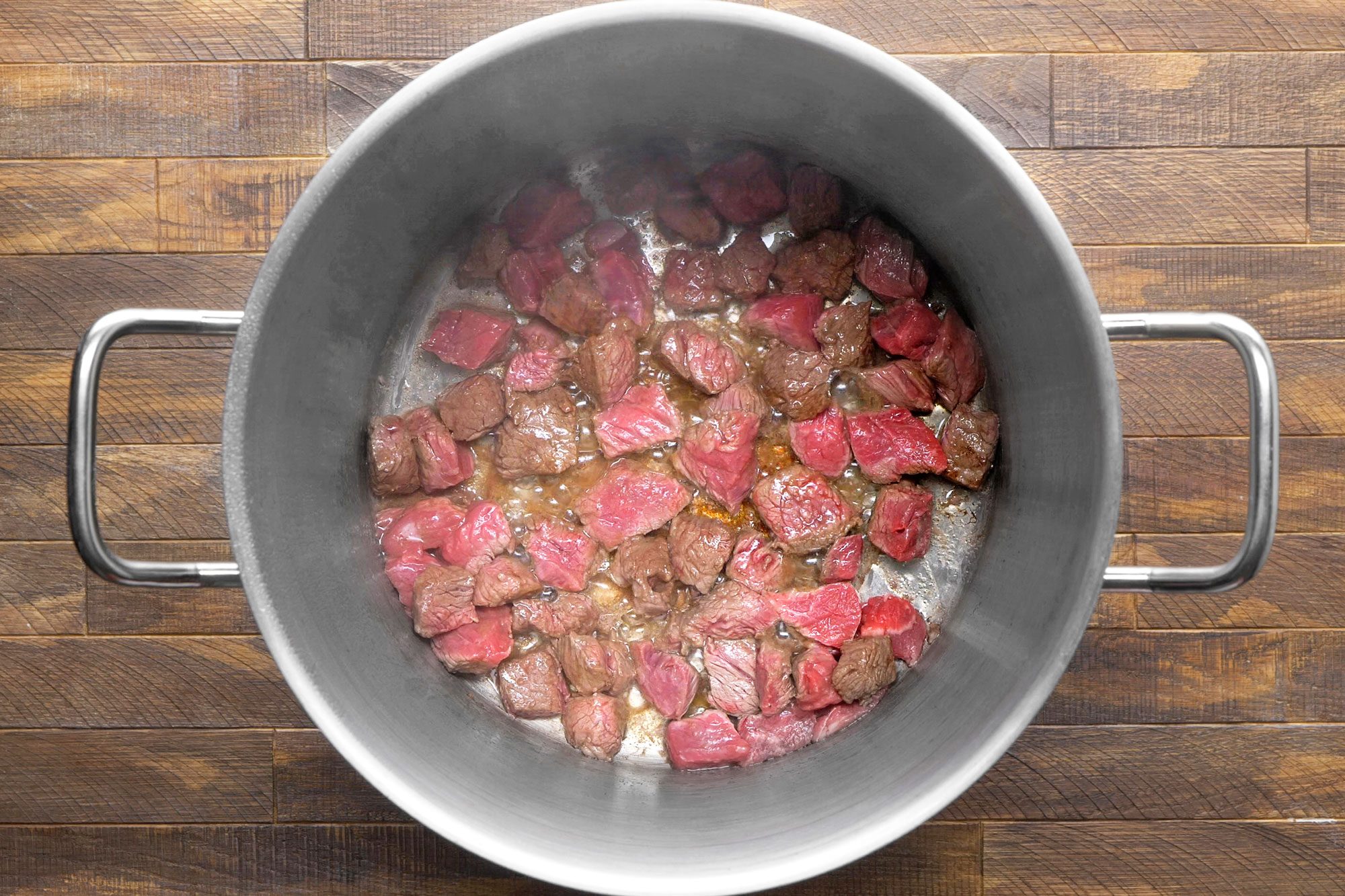 Large stainless steel pot is filled with browned ground beef