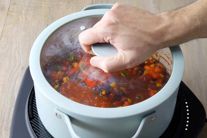 Boiling vegetables and spices in a large pan to make Vegetarian Chili