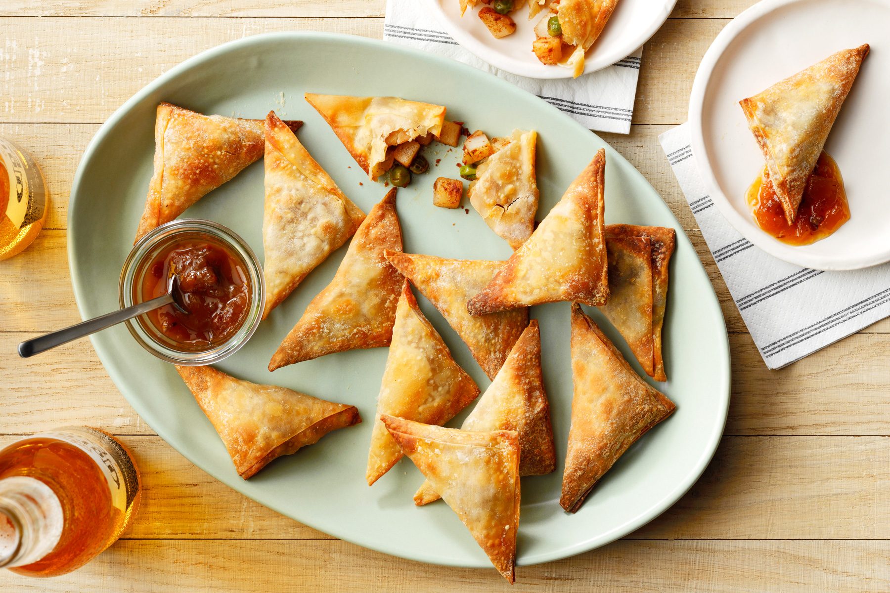 A plate of triangular Air Fryer Samosas with a small bowl of dipping sauce
