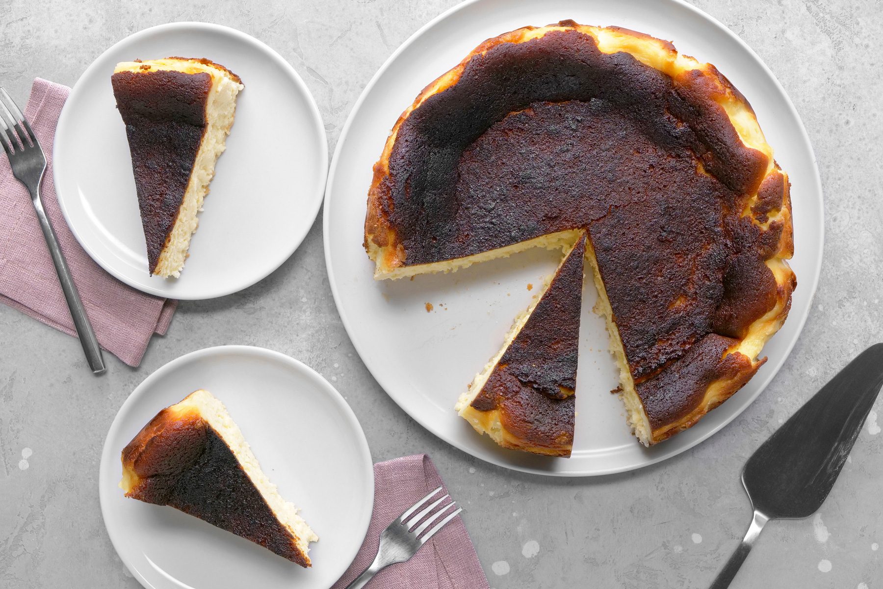 Overhead shot of a perfectly baked Basque cheesecake, highlighting its caramelized top and rustic, slightly cracked edges.