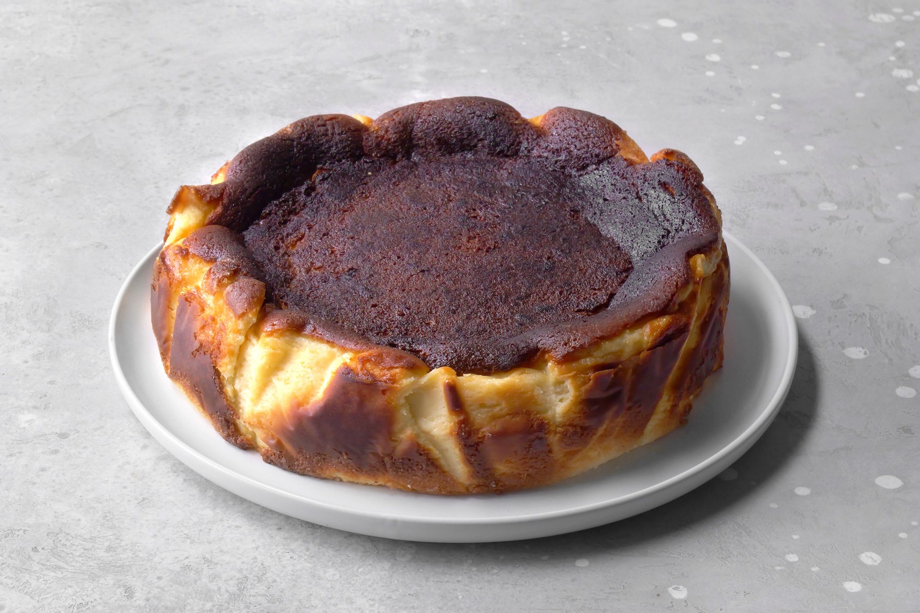 High-angle shot of a freshly baked Basque cheesecake, showcasing its golden-brown top and creamy, soft center.
