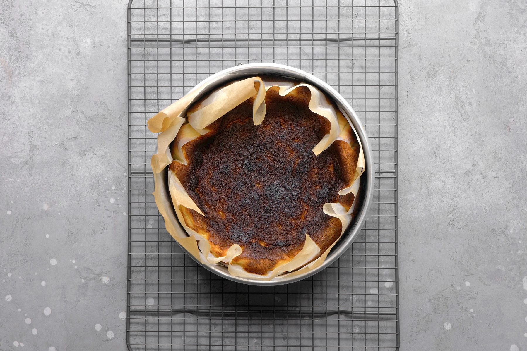 Overhead shot of a perfectly baked Basque cheesecake, highlighting its caramelized top and rustic, slightly cracked edges.