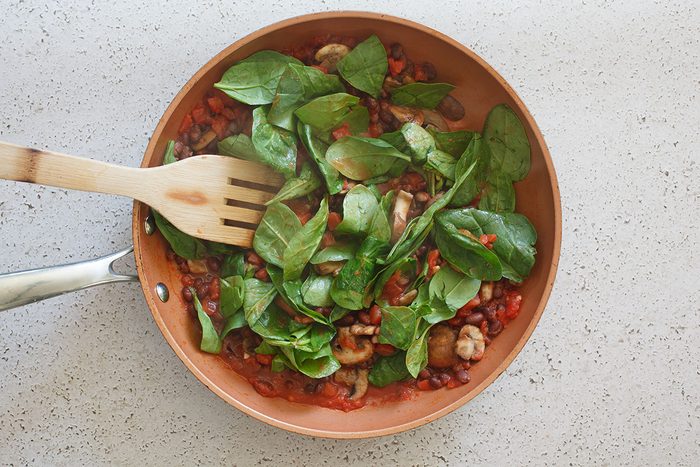 Vegetables cooking in skillet, spinach, mushrooms, tomatoes