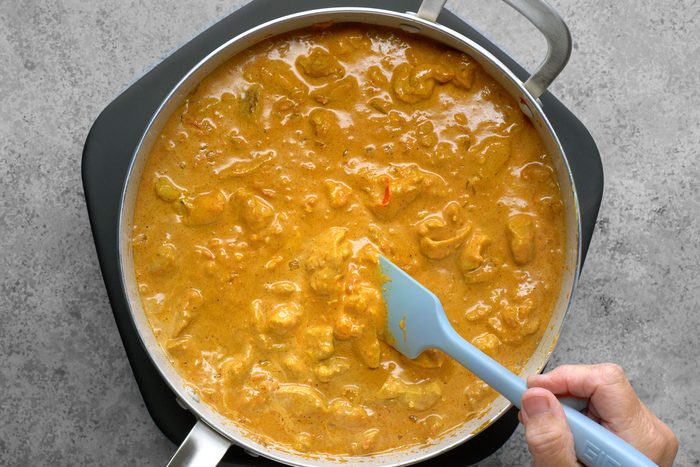 Chicken pieces are boiling in the same skillet, absorbing the flavors of the sauce as they cook. The bubbling liquid creates a fragrant aroma, while the chicken gradually transforms, becoming tender and infused with the rich, savory blend of spices and ingredients.
