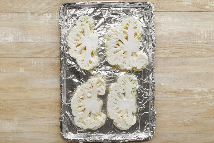 Cauliflower cut into slices and placed on a foil covered baking pan