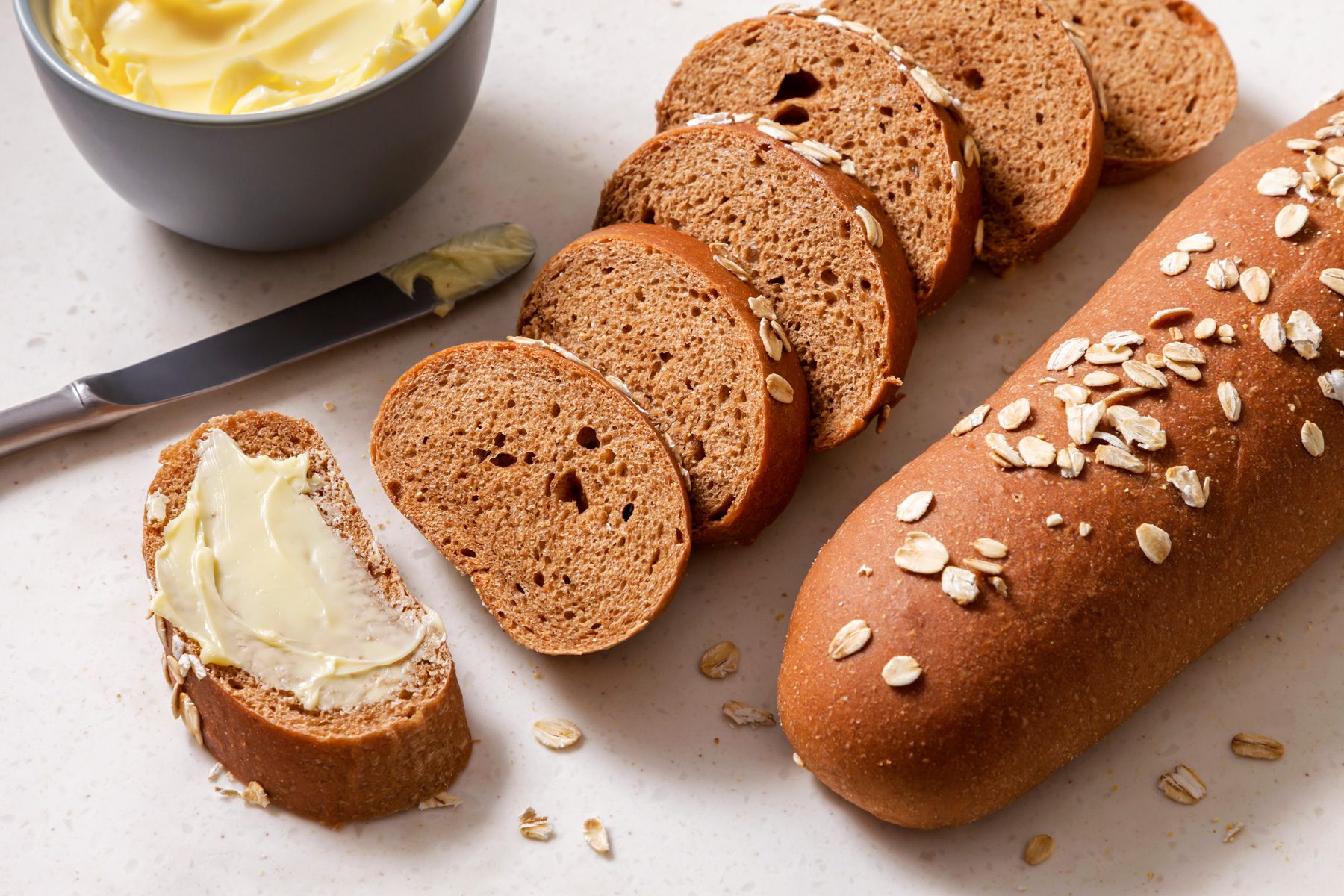 Close shot of Copycat Cheesecake Factory Brown Bread; slice and serve warm with butter; knife; white board; grey surface;