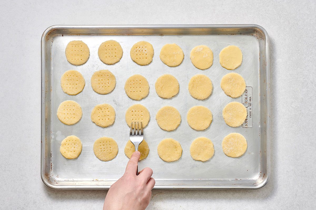 Cookies placed on a greased baking sheet, each pricked four times with a fork