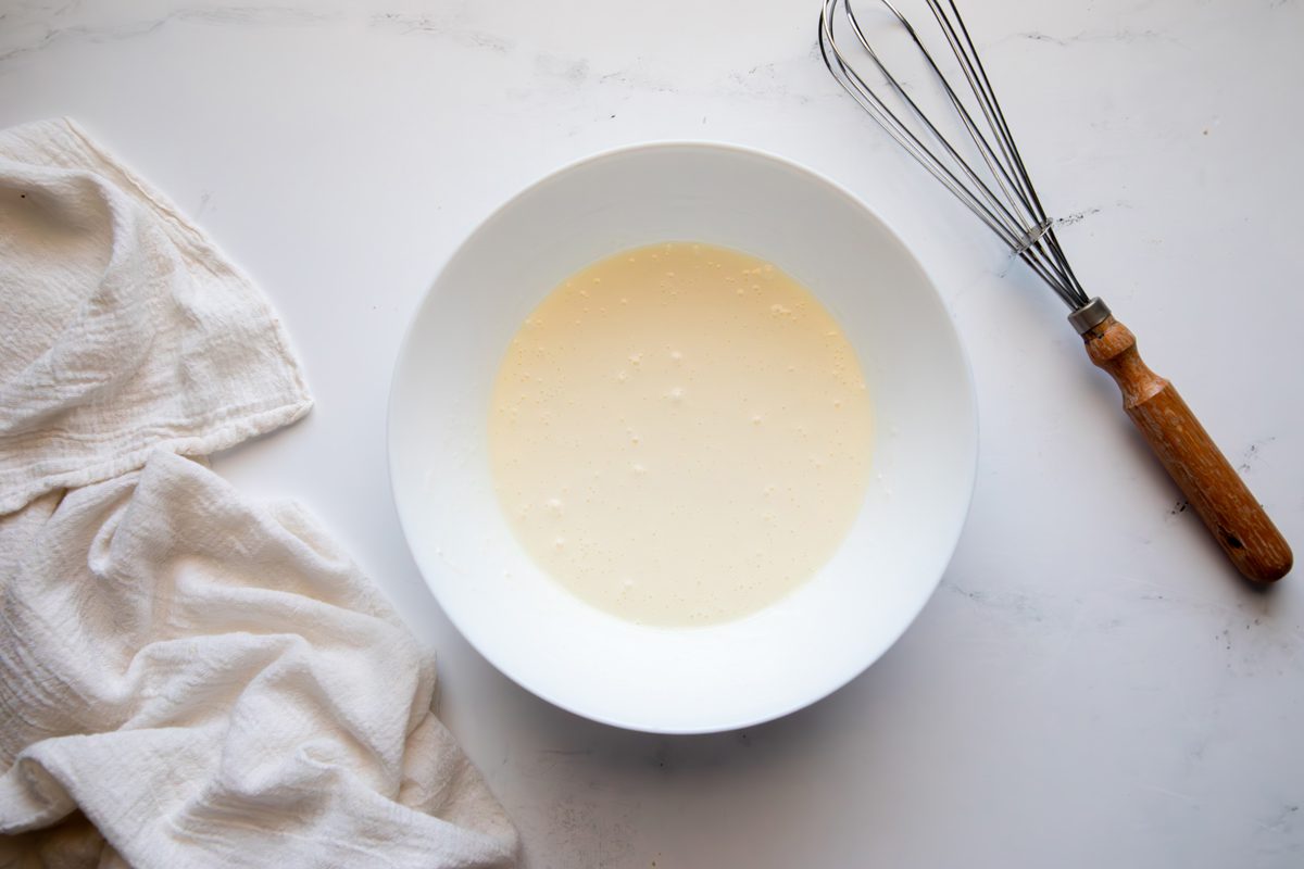 Overhead shot for Taste of Home Creamy Cucumber Salad, dressing mixed in a large bowl.