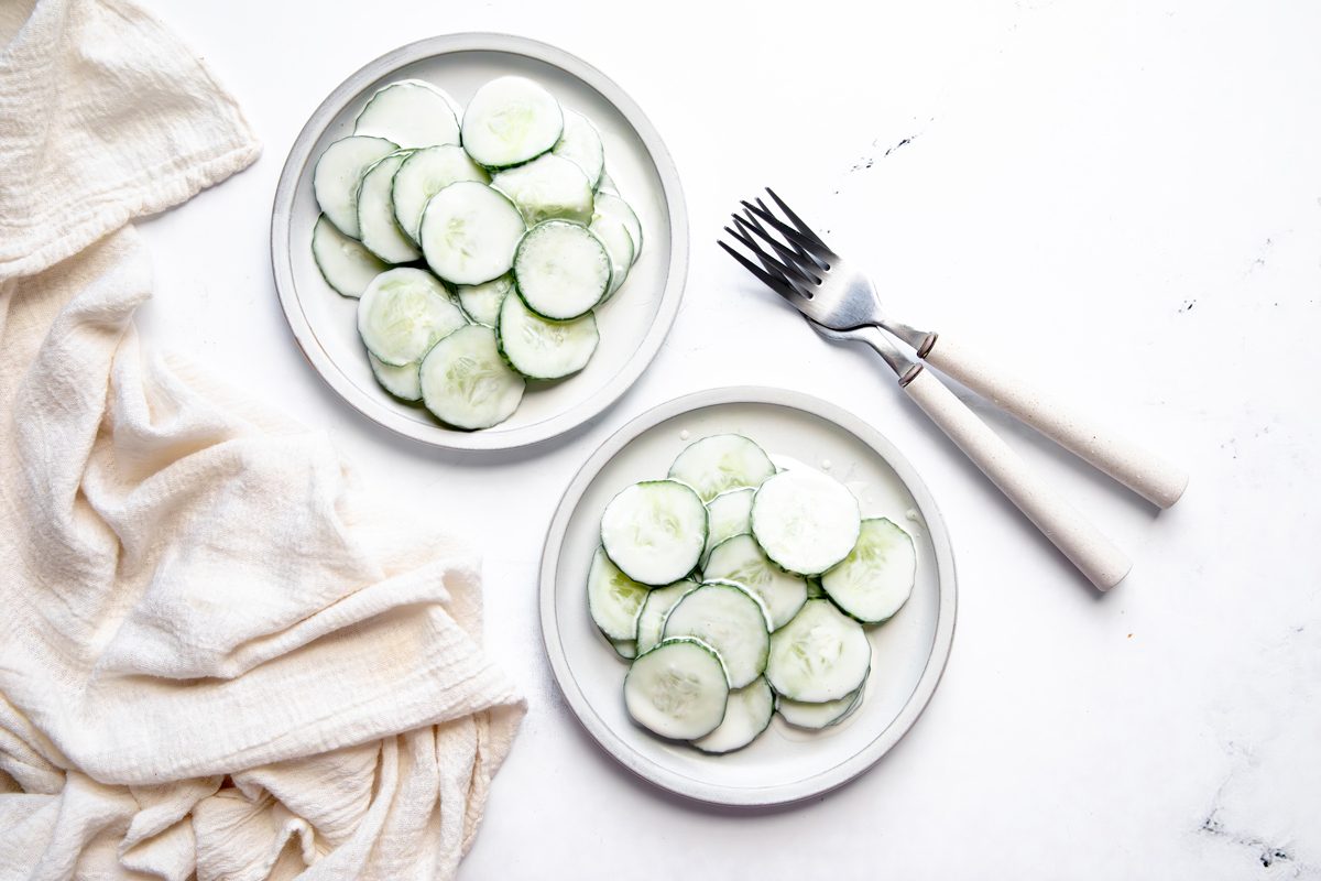 Overhead beauty shot for Taste of Home Creamy Cucumber Salad on plates being served.