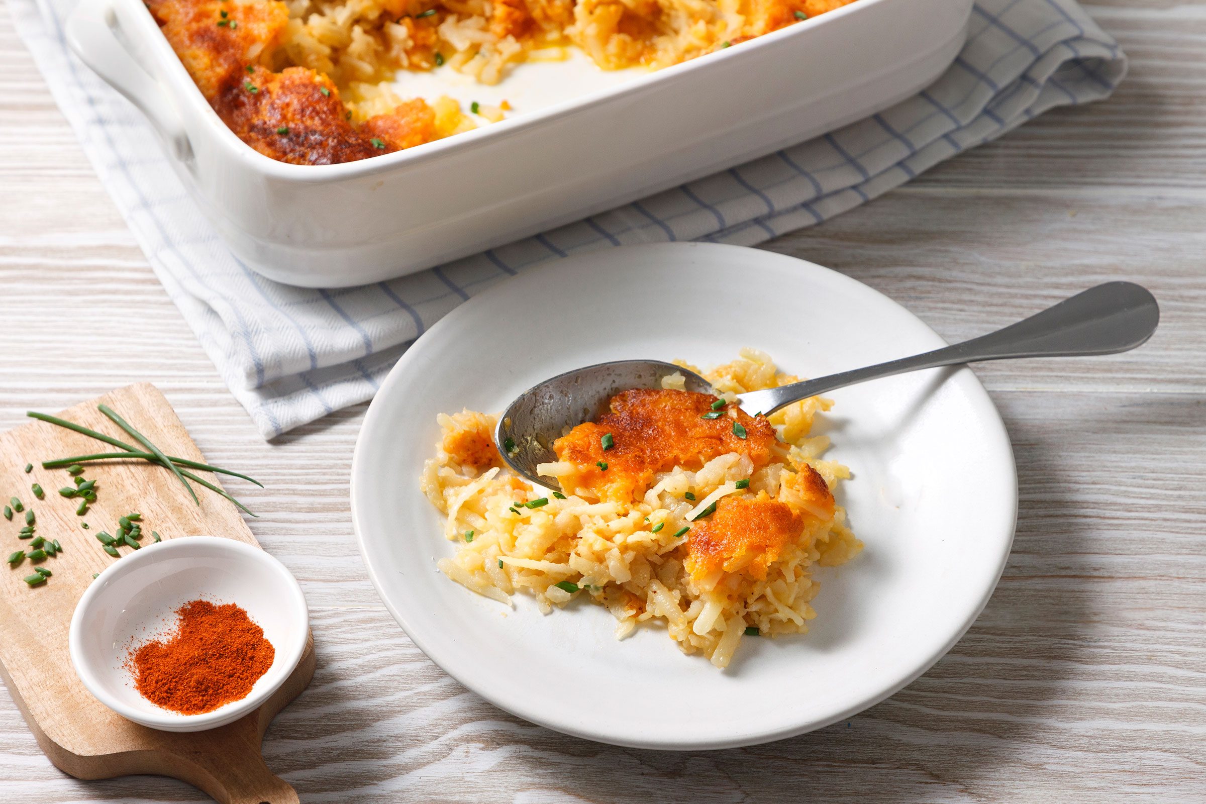 Delmonico Potatoes served on a plate with some spice on the side