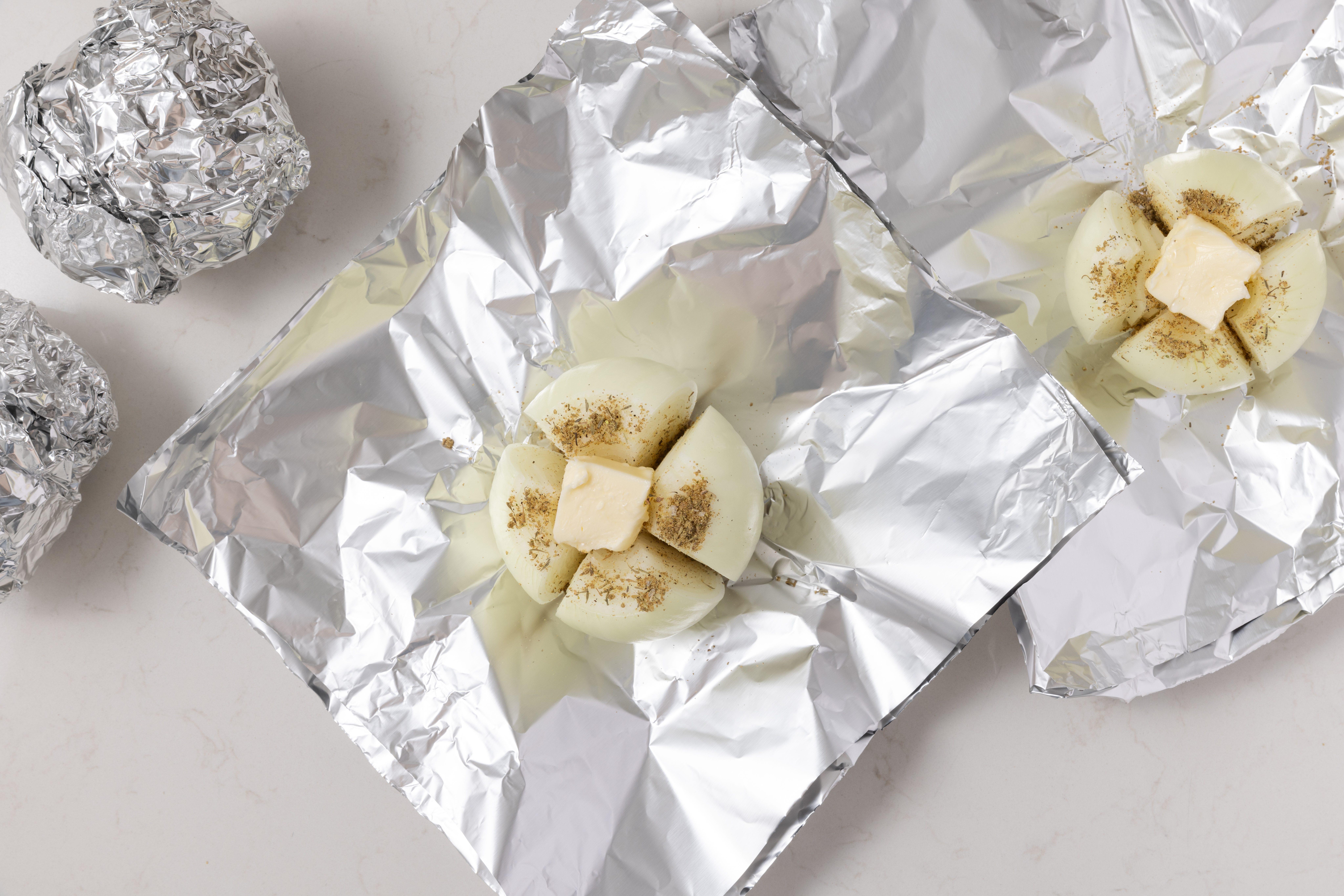 Onions being seasoned and wrapped in heavy-duty foil.