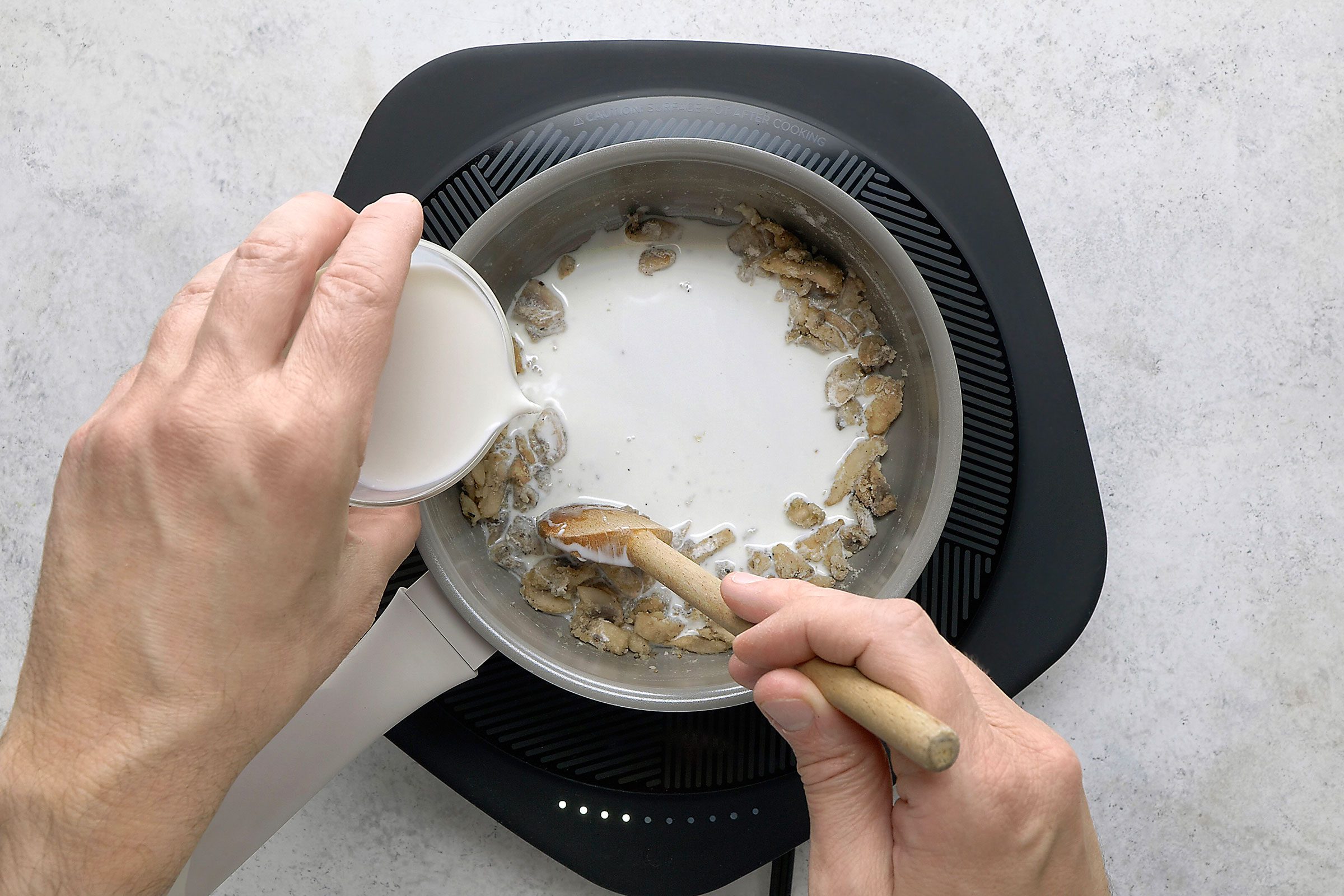 Adding cream to sautéed mushrooms in a saucepan