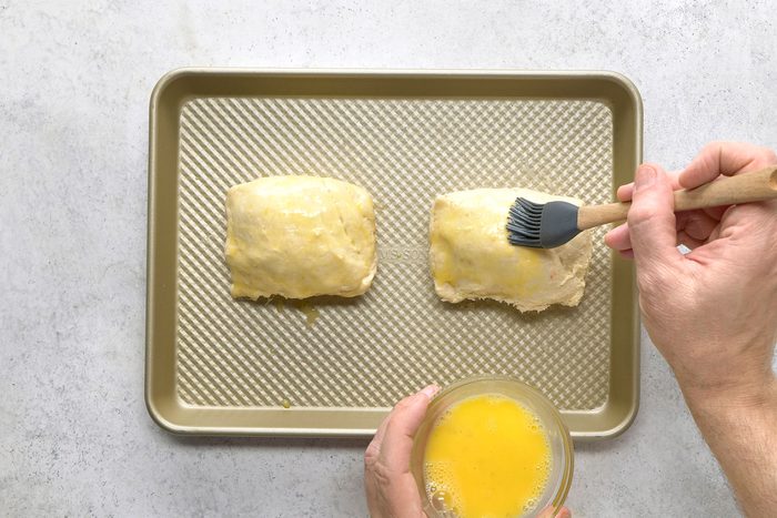 Brushing egg whites on dough sheets with beef inside