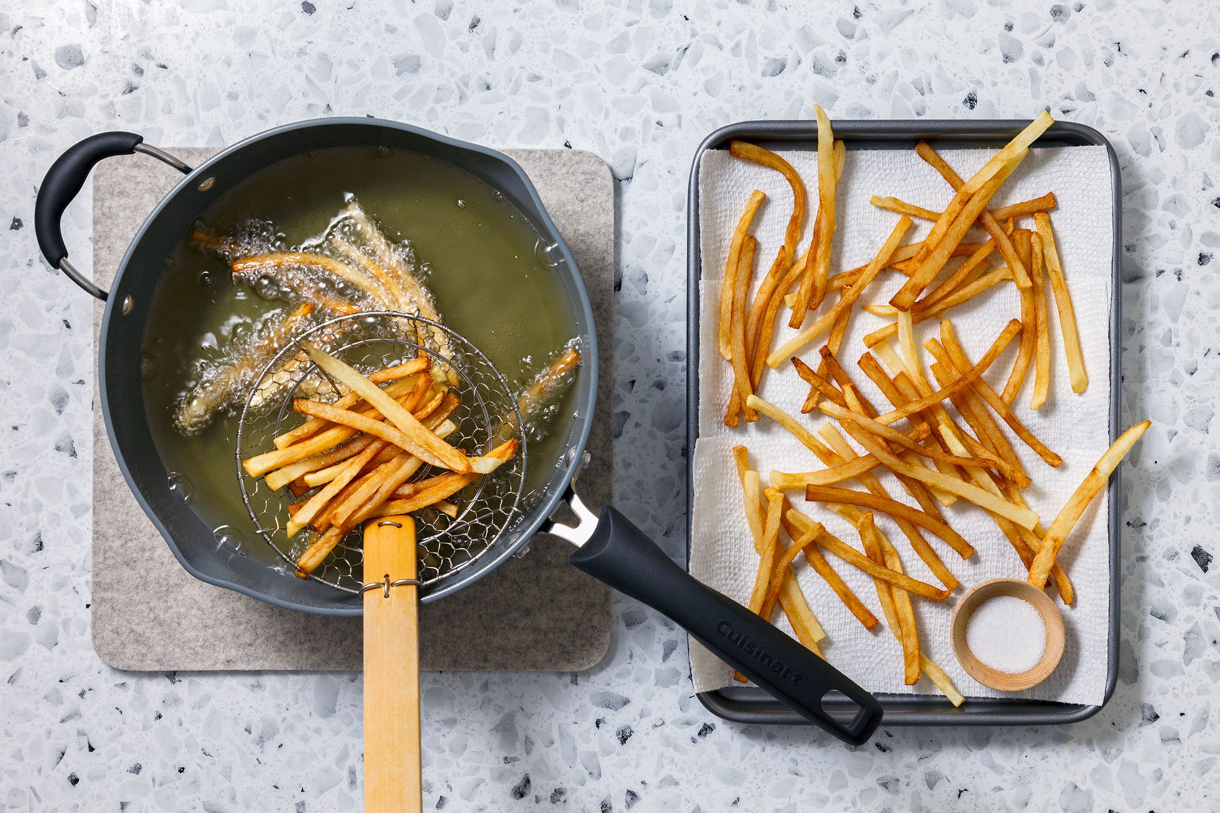Frying potato strips in a oil in a large iron skillet until they are golden brown