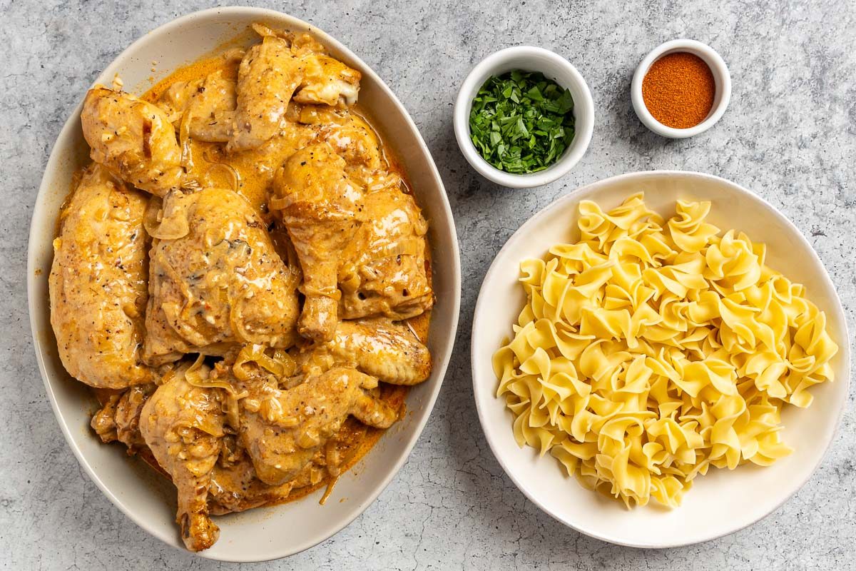 Taste of Home Hungarian Chicken Paprikash photo of the cooked chicken with optional toppings and side of noodles.