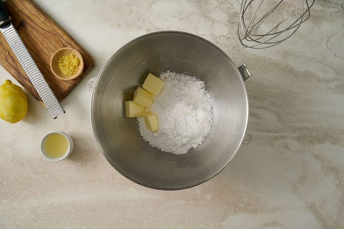 Overhead view of lemon frosting made with softened butter, confectioners’ sugar, lemon juice, and lemon zest, being spread on the cooled lemon pound cake for the Taste of Home Lemon Pound Cake recipe.