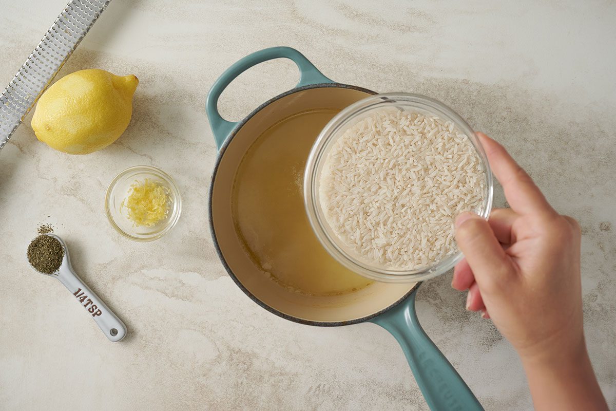 Overhead view of rice, basil, and lemon zest about to be be stirred into the boiling liquid for the Taste of Home Lemon Rice recipe.