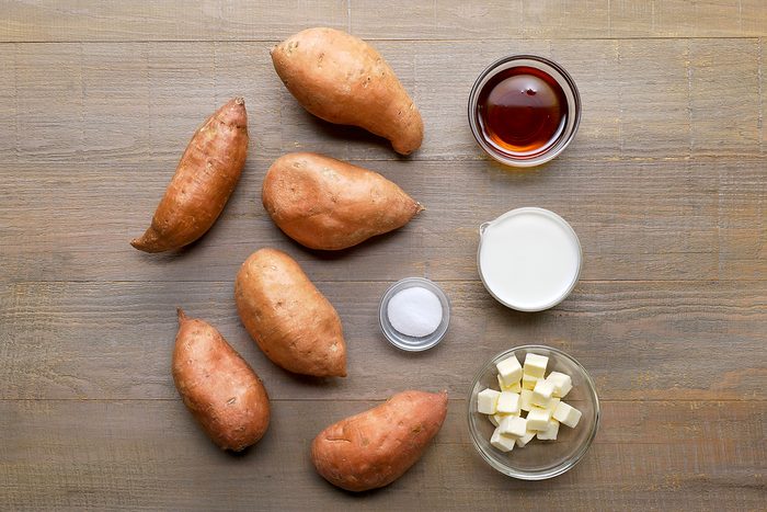 overhead shot of Mashed Sweet Potatoes ingredients placed over wooden background;