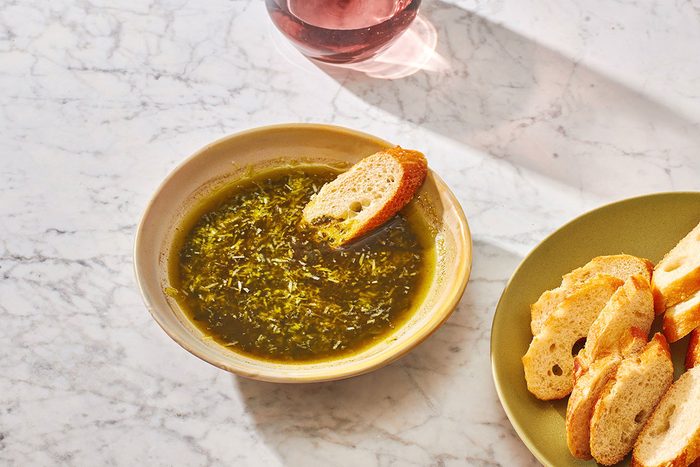 Pesto dipping oil in a shallow serving bowl, served with sliced baguette