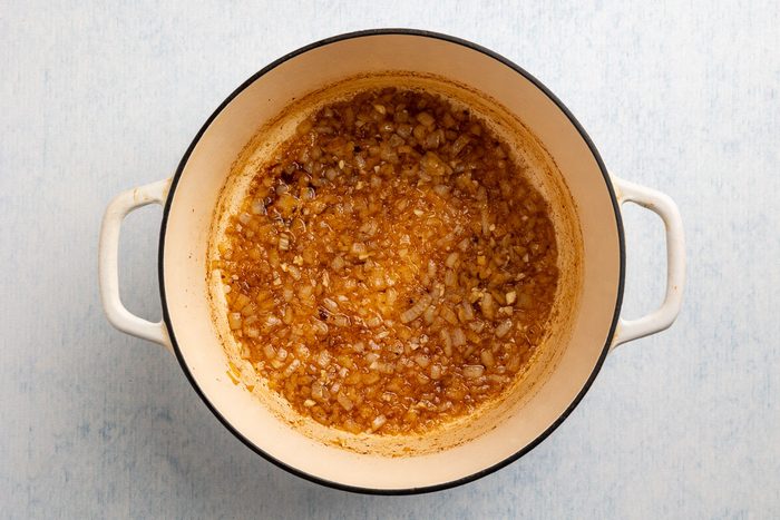 Taste of Home Pinto Bean Recipe photo of garlic and onion sauteed in a dutch oven.