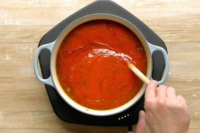 Crushed tomatoes, water, tomato paste, salt, and chopped basil combined in a Dutch oven.