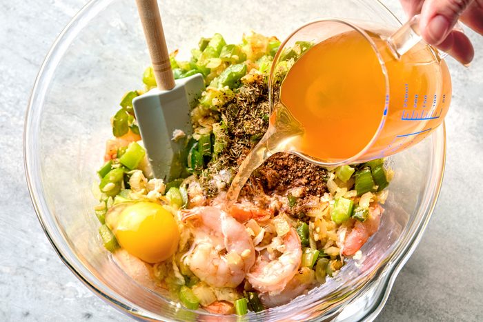 overhead shot of Adding onion mixture to the large bowl with shrimp and crab, Added Cajun seasoning, thyme, salt, pepper, stock and egg; stir to combine