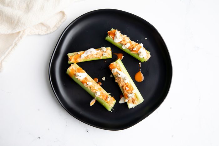 Beauty shot for Taste of Home Shredded Buffalo Chicken with mixture on celery ribs dressed with blue cheese and ranch dressing.