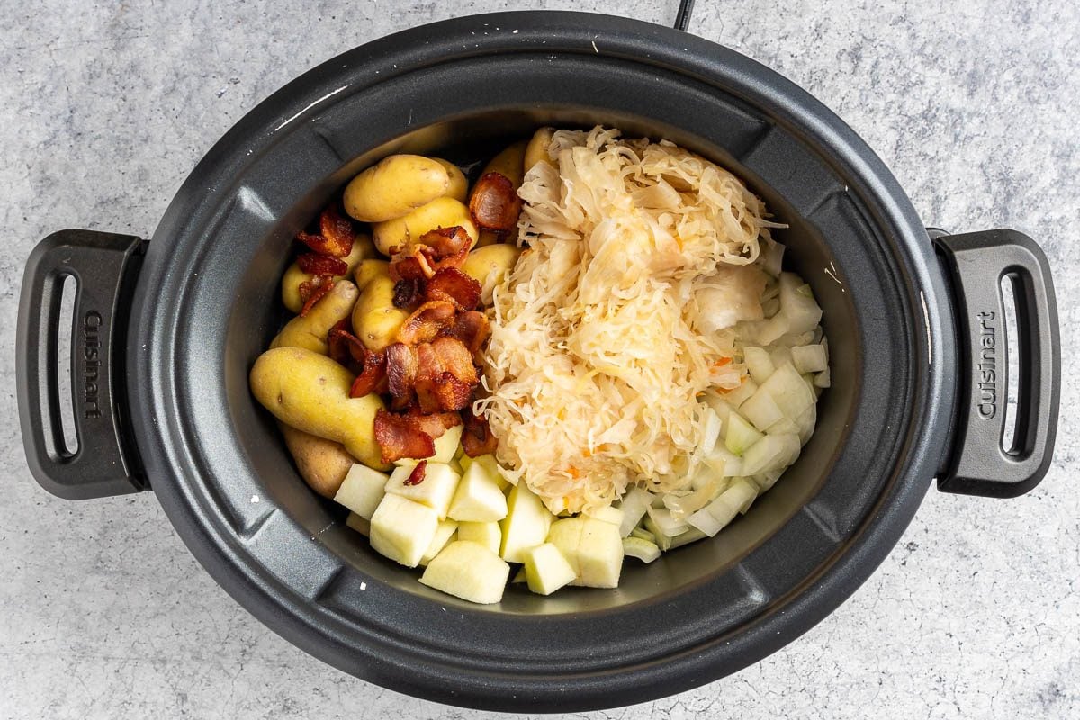 Taste of Home Slow Cooker Pork and Sauerkraut photo of the sauerkraut, potatoes, onion, apple and bacon in the slow cooker.