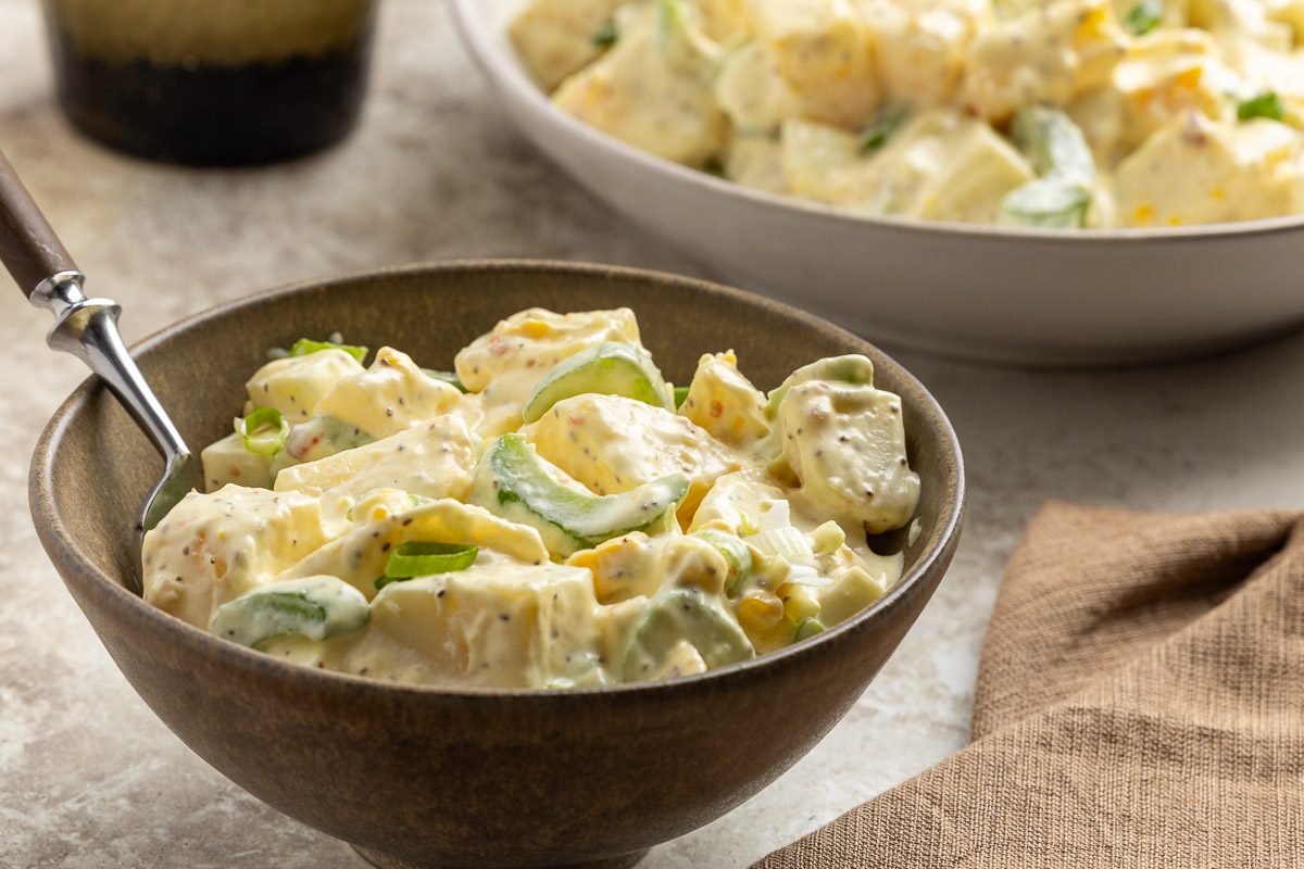 Taste of Home Sour Cream Potato Salad recipe photo of the finished potato salad in serving dish and served in a bowl.