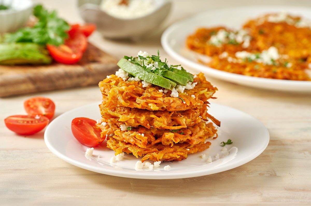 Close-up horizontal shot of the Taste of Home Sweet Potato Fritters, highlighting the crispy edges and tender interior with queso fresco.