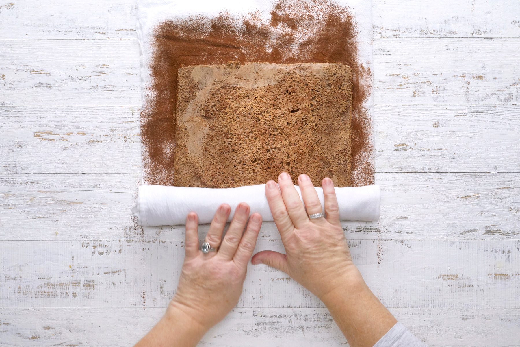 Turning the cake onto a kitchen towel dusted with cocoa powder.