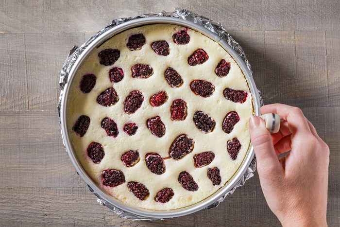 Loosening the sides of baked cheesecake with a knife in pan
