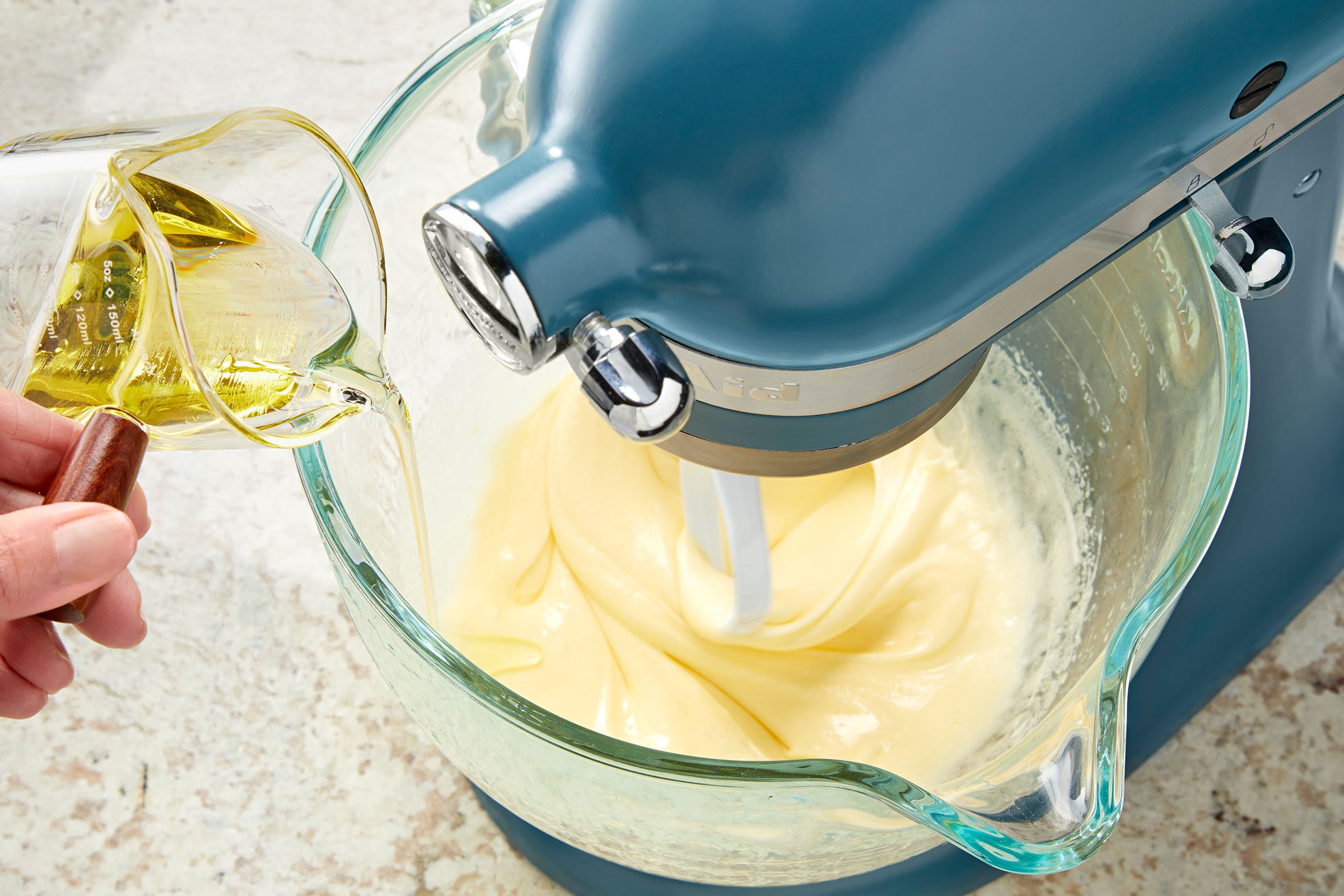 Adding olive oil to the beaten eggs and sugar mixture