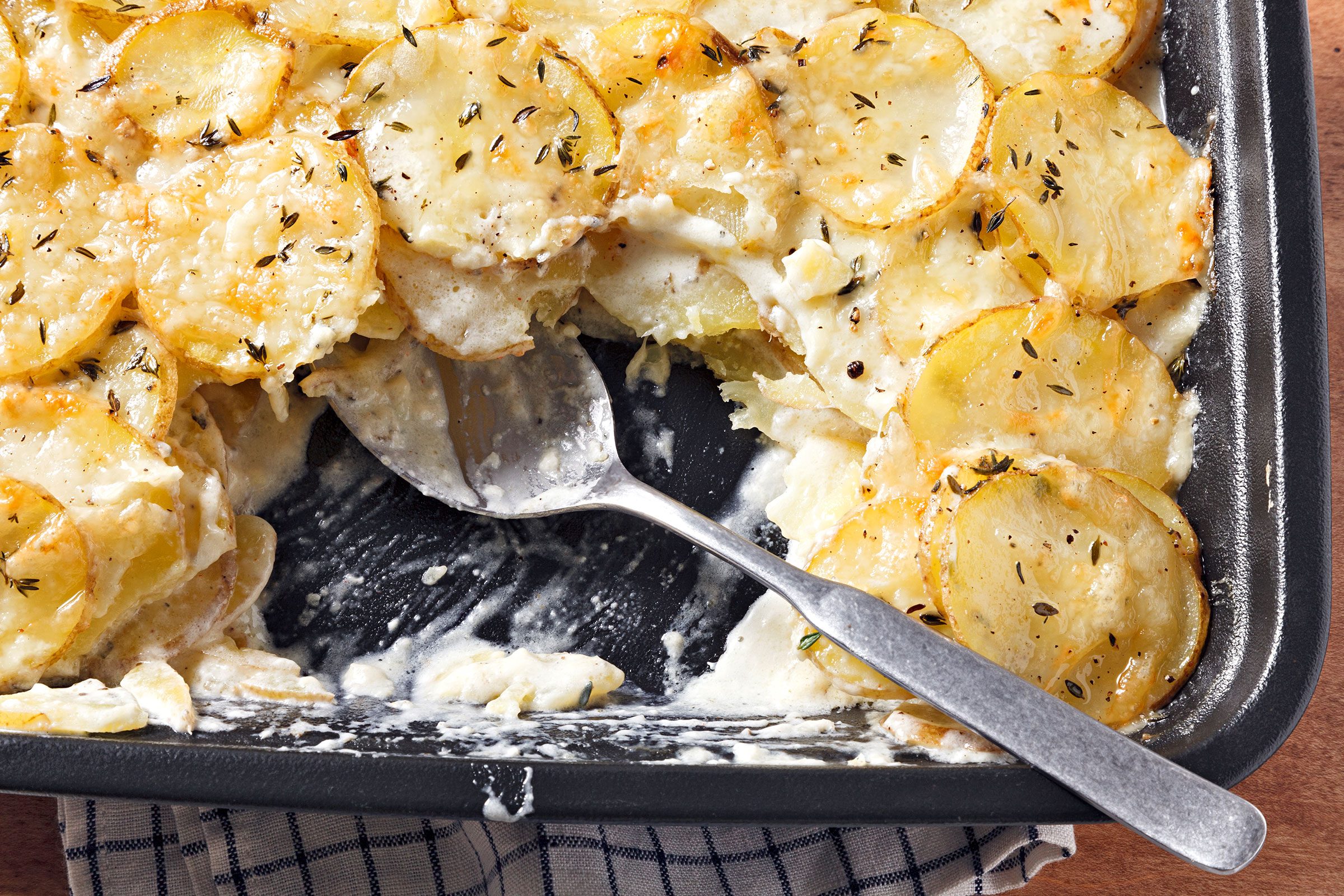 Potatoes Au Gratin Gruyere in a dish with a serving spoon