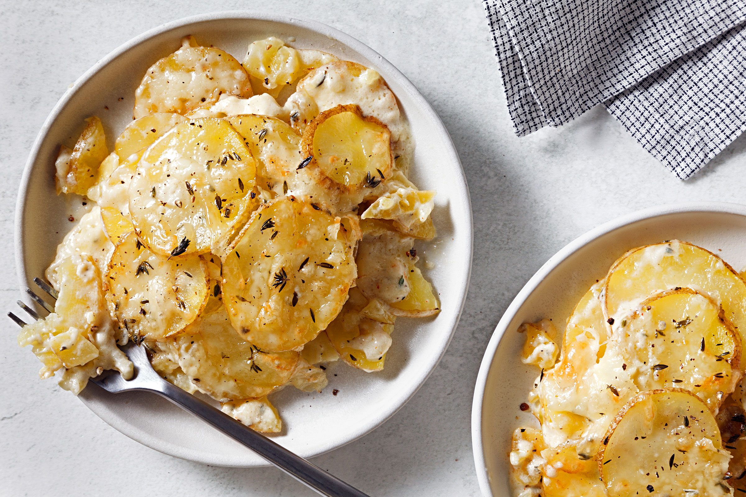 Potatoes Au Gratin Gruyere served on a white plate with a fork to eat