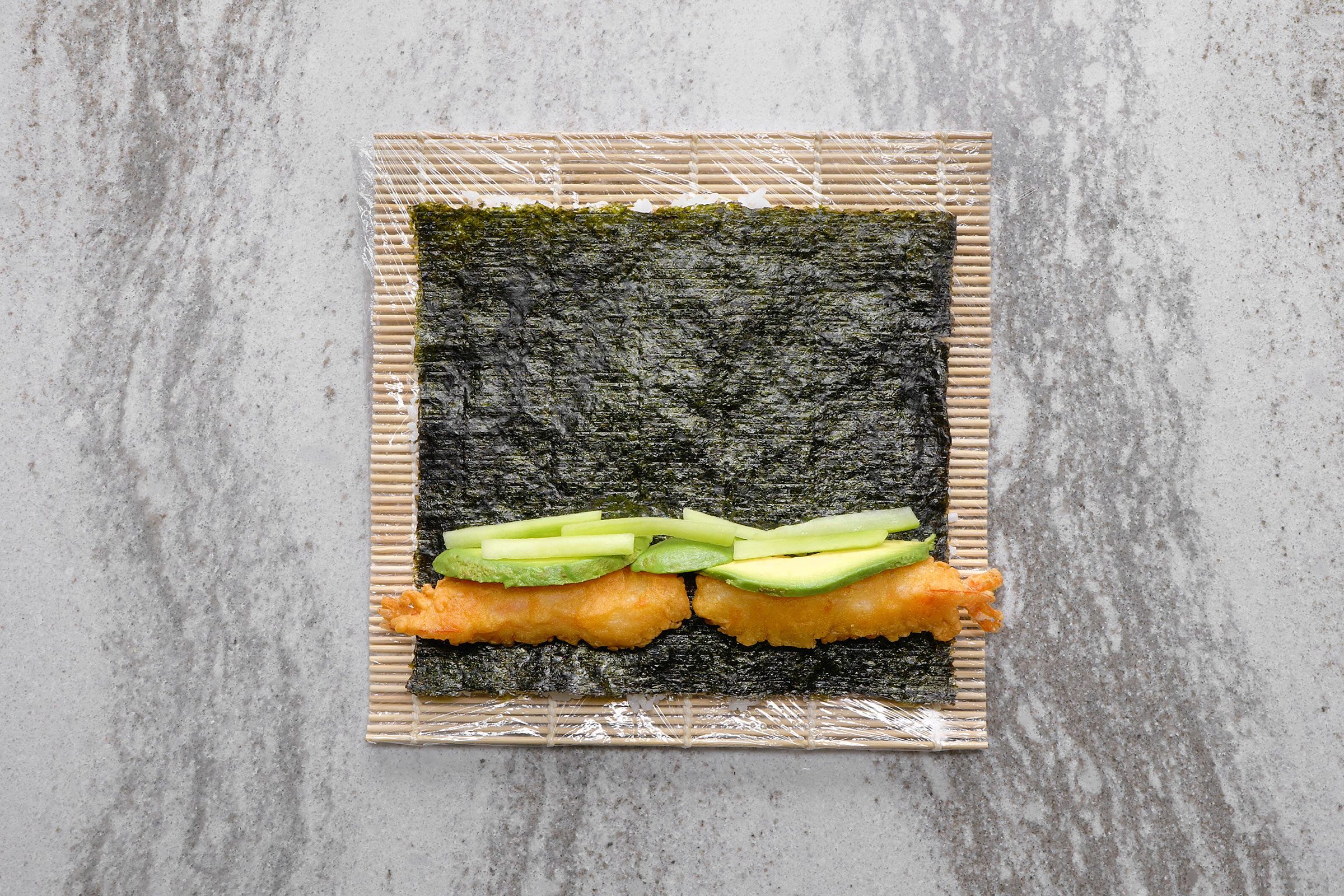 Cucumber, avocado and shrimps placed upon the nori sheet. and rice
