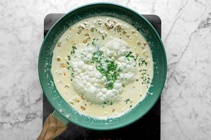 Overhead shot of add shallot to same pan; cook and stir over medium heat until tender; add cream; stirring to loosen browned bits from pan; Increase heat to medium-high; cook until slightly thickened; stir in 2 teaspoons tarragon; lemon juice and remaining salt; induction; marble surface