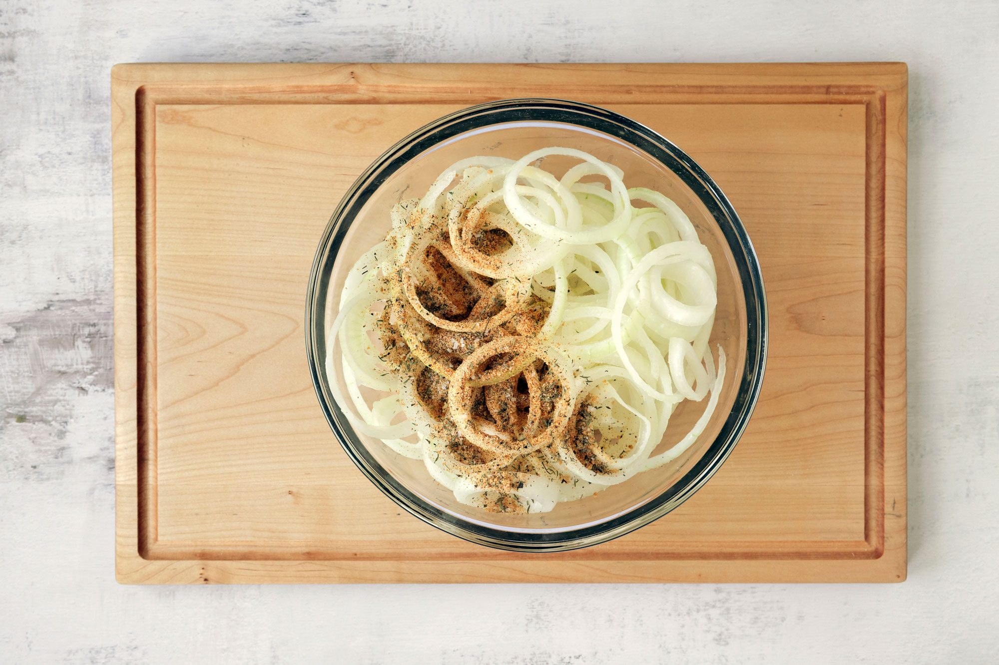 Add the sliced onions to the bowl and toss to coat them in butter