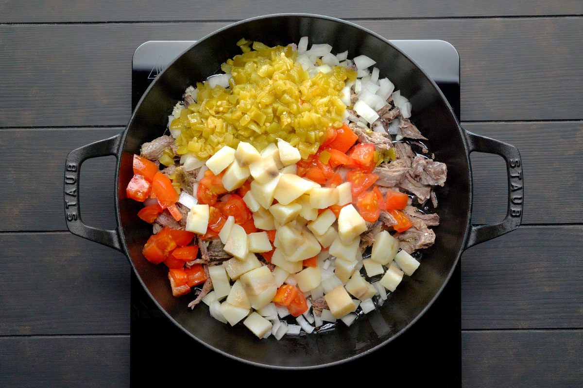 In a large skillet, heat bacon grease over medium heat. Add beef, onion, garlic, tomato, chilies and potato.