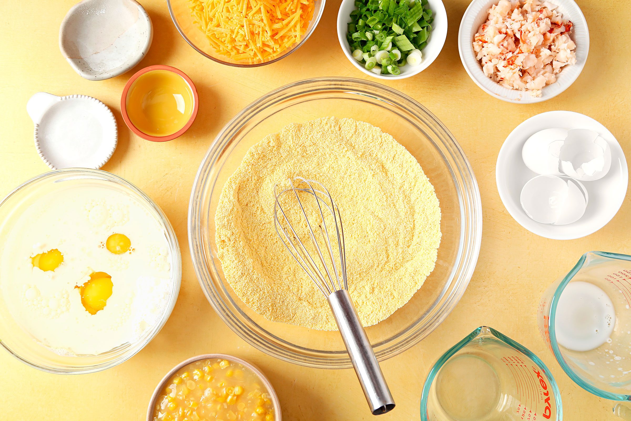 Cornmeal in a bowl with Cornbread ingredients around it in small bowls