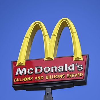 McDonald's sign with the golden arches and a "Billions and billions served" slogan on a red slab, with a blue sky background