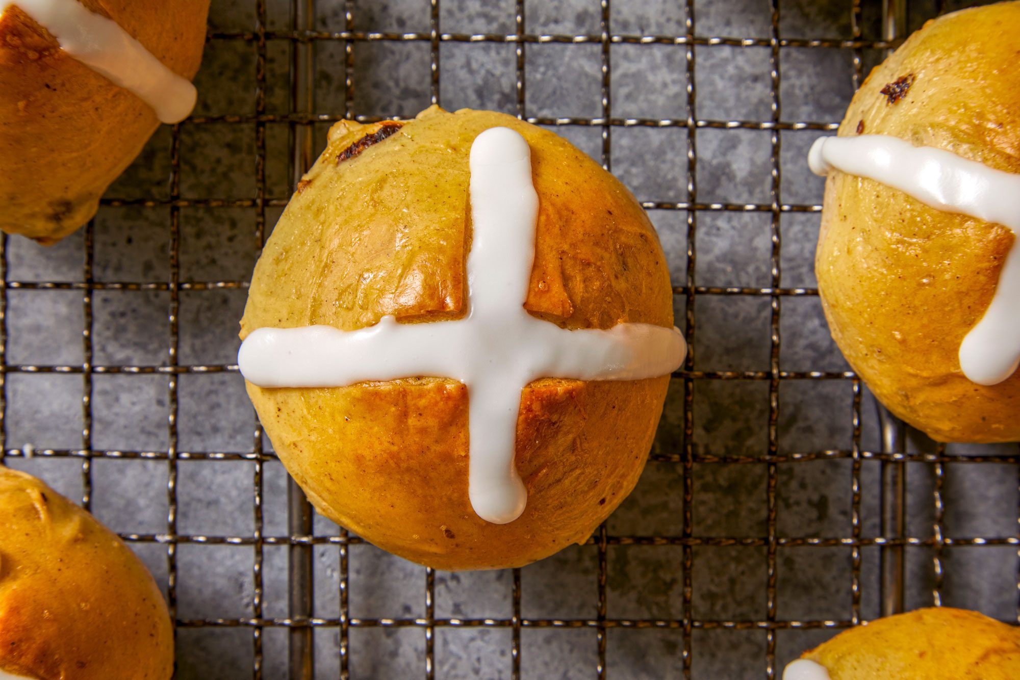 overhead close-up view of Traditional Hot Cross Buns; the buns are on a wire rack
