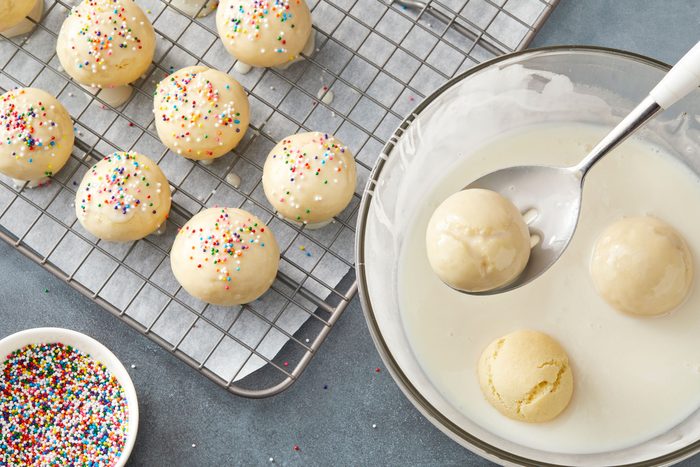 quickly dip 2 or 3 at a time into glaze; Remove with a slotted spoon or tongs; place on wire racks to drain; Immediately top with sprinkles