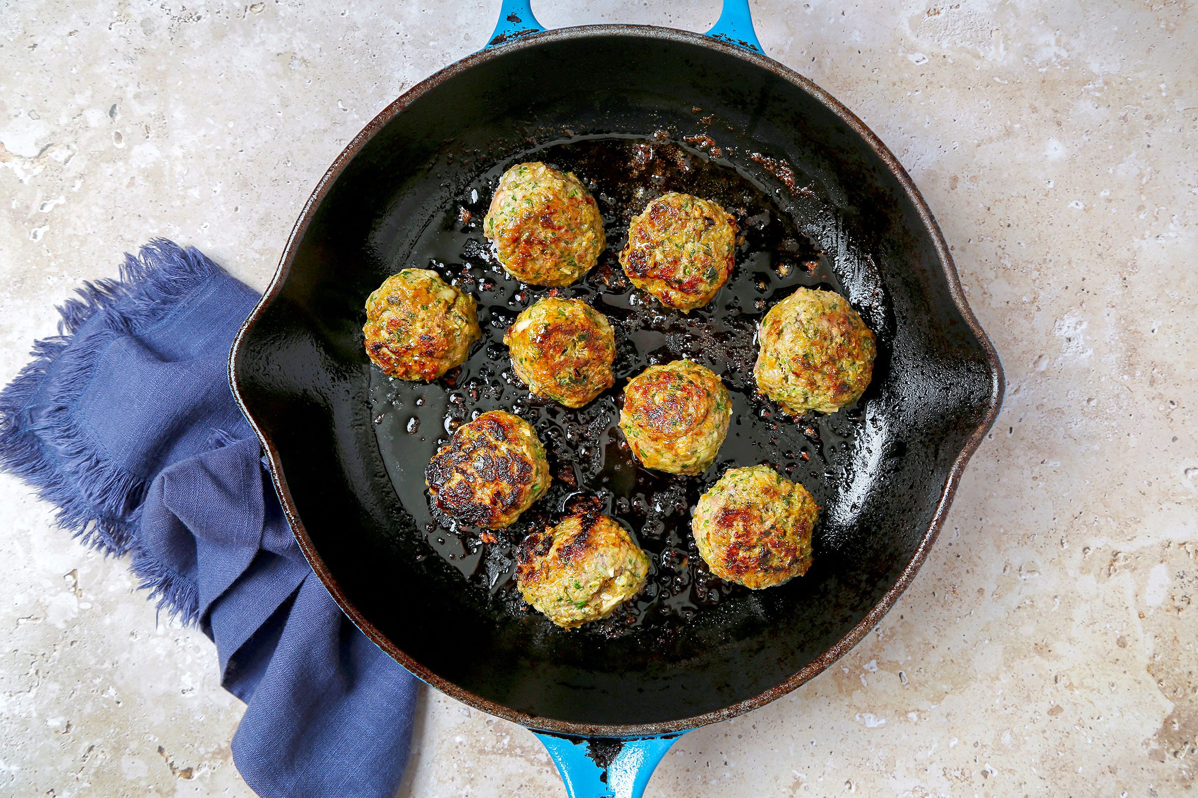 Browned meatballs cooked in oil in a large skillet