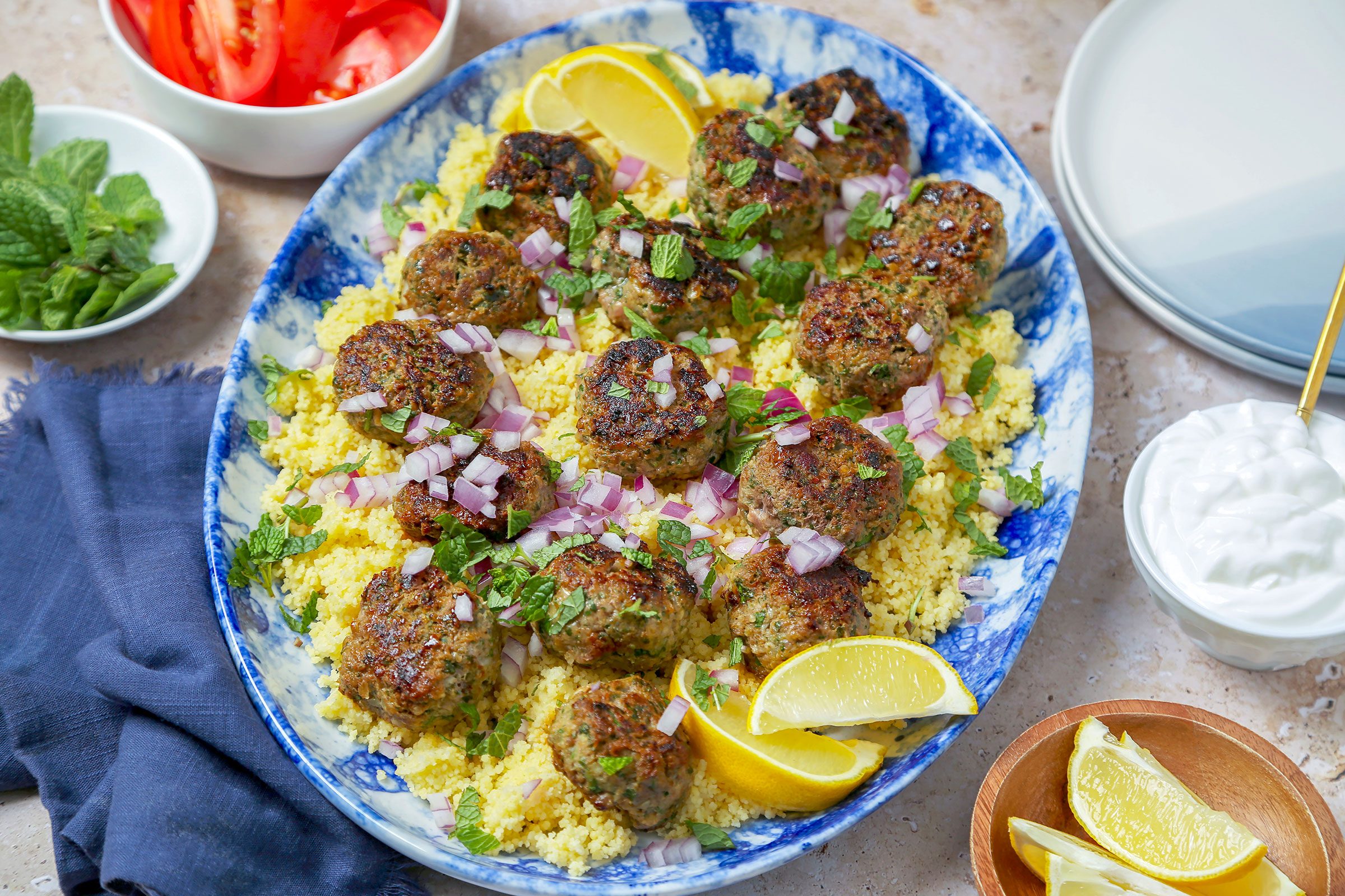 Kofta Meatballs in a plate with some veggies, lemon and greek yoghurt on side