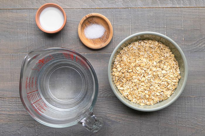 overhead shot of a bowl of oatmeal, a bowl of blueberries, and two spoons on a wooden table