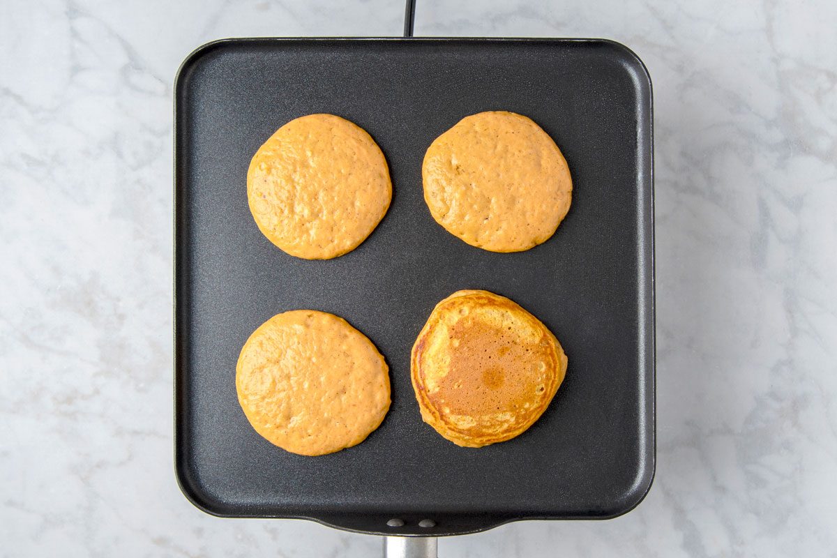 Overhead shot of pour batter by 1/4 cupfuls onto a greased skillet over medium heat; Turn when bubbles form on edges of pancakes; cook until the second side is golden brown; marble surface;