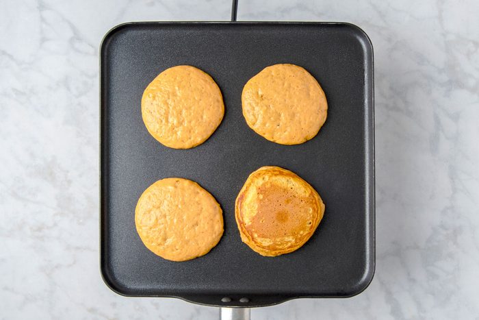 Overhead shot of pour batter by 1/4 cupfuls onto a greased skillet over medium heat; Turn when bubbles form on edges of pancakes; cook until the second side is golden brown; marble surface;